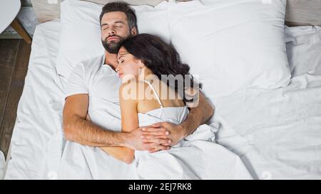 vista dall'alto della giovane coppia che si abbraccia mentre dormiva a casa Foto Stock