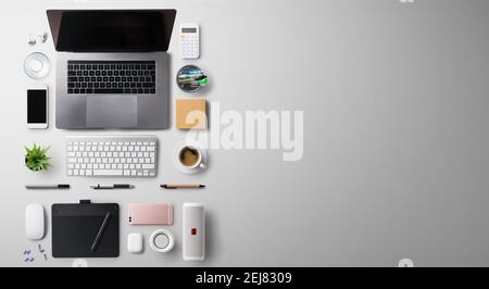 Scrivania da ufficio con vista dall'alto e piano con computer portatile e materiali di consumo su sfondo grigio. Foto Stock