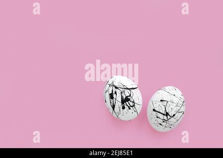 Due uova bianche in macchie nere su sfondo rosa con una copia dello spazio. Pasqua. Minimalismo. Foto Stock