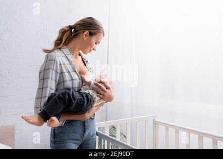 felice giovane donna lulling piccolo figlio vicino al presepe a casa Foto Stock