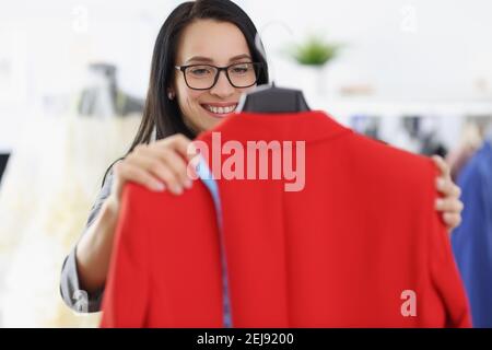 Donna seamstress che tiene in mano una giacca rossa Foto Stock