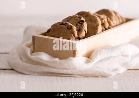 Biscotti alla vaniglia e cioccolato in una scatola di legno con un tovagliolo bianco. Foto Stock