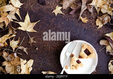 Pezzi di pastafrola su un piatto bianco con una forchetta e foglie di albero. Foto Stock