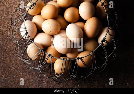 Uova in un cestino cablato su sfondo scuro. Foto Stock