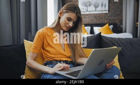 freelance che usa il computer portatile mentre si siede sul divano nella camera d'albergo Foto Stock