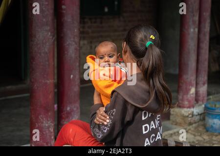 Utttar Pradesh. 05-15-2018. Giovane ragazza che tiene un bambino a casa sua in un villaggio rurale dell'India. Foto Stock