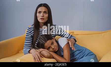madre che si prende cura di calmare la figlia sconvolta che giace sul cuscino Foto Stock