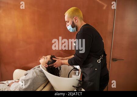 Cliente che ha la sua testa massaggiata da un coiffeur Foto Stock