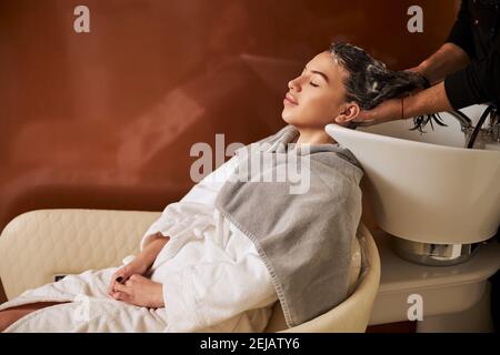 Stilista maschile professionale che lava la testa di una donna Foto Stock