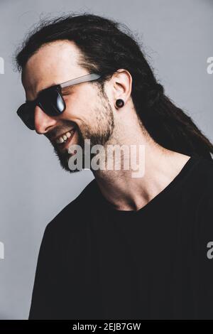 Ritratto di un giovane felice con dreadlock e occhiali da sole scuri. Foto Stock