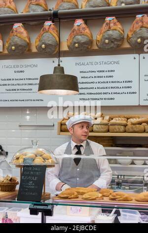 Un uomo che serve dietro il bancone al negozio di delicatessen Simoni Vendita di formaggio e prosciutto italiano a Bologna Italia Foto Stock