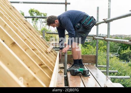 Operai che costruiscono una stanza sul tetto di una proprietà residenziale che era un bungalow. Foto Stock