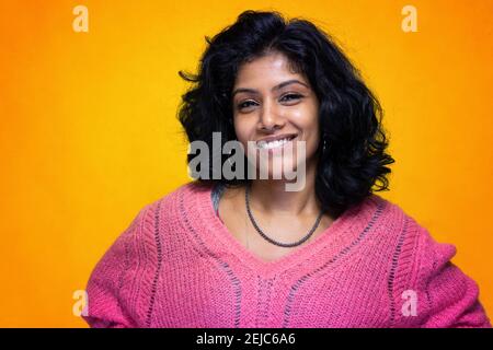 Bella Sri Lanka ragazza posa in piedi con giallo luminoso sfondo- La giovane donna sorride Foto Stock