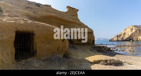 Vista delle grotte e delle abitazioni in pietra arenaria in una baia idilliaca E spiaggia sulla costa o Murcia Foto Stock