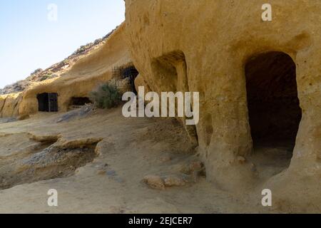 Vista delle grotte e delle abitazioni in pietra arenaria in una baia idilliaca E spiaggia sulla costa o Murcia Foto Stock