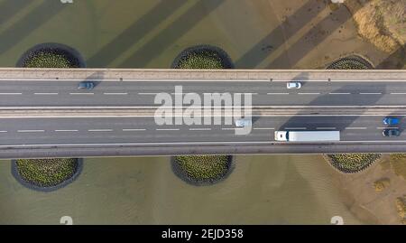 Vista da un drone che guarda giù sul traffico su un ponte stradale che attraversa un grande fiume a Suffolk, Regno Unito Foto Stock