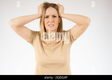 Ritratto di giovane infastidita in t-shirt casual con colletto tirare i capelli e impazzire Foto Stock