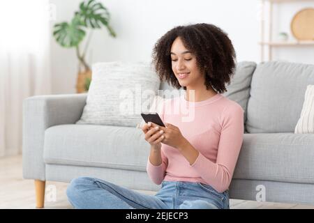 Felice piacevole millennial afroamericana donna rilassante in una vita confortevole camera Foto Stock
