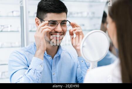 Optometrist che aiuta il ragazzo sorridente a scegliere gli occhiali di correzione Foto Stock