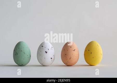 Quattro belle uova di Pasqua color pastello al cioccolato, su sfondo bianco con spazio per la copia Foto Stock