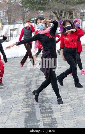 Una donna americana cinese aggraziata e snella conduce una lezione di danza in una fredda giornata invernale. In un Flushing Queens, parco di New York. Foto Stock
