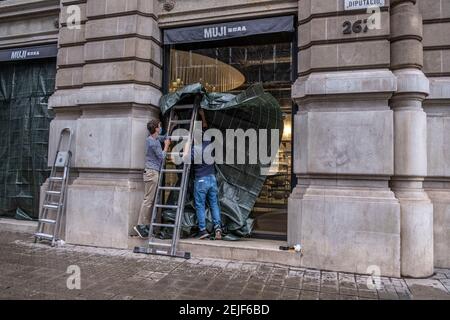 Barcellona, Spagna. 22 Feb 2021. Gli operatori sono visti rinforzare le finestre del negozio Muji su Passeig de Gràcia contro il vandalismo.più di 50 negozi hanno subito danni alle loro vetrine e alcuni sono stati saccheggiati su Passeig de Gràcia durante le rivolte a seguito delle dimostrazioni per la libertà di rapper Pablo Hasel. Credit: SOPA Images Limited/Alamy Live News Foto Stock