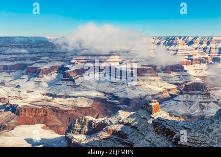 Grand Canyon al mattino, coperto di neve. Cielo blu; nuvole sul bordo del canyon. Foto Stock