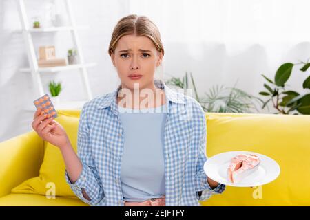 Donna triste con pillole di contenimento allergico e salmone Foto Stock