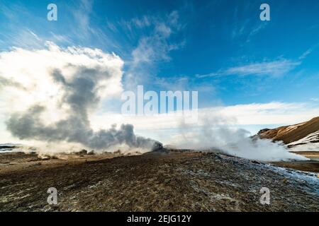 Namafjall Hverir zona geotermica in Islanda. Splendido paesaggio di valle dello zolfo con fumarole fumanti e cielo blu nuvoloso, sfondo di viaggio Foto Stock