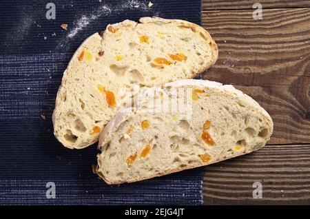 Due fette di pane di ciabatta con albicocca secca e semi di zucca su rustico tavolo di legno, vista dall'alto Foto Stock