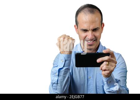 Uomo maturo in abbigliamento formale giocando sul suo smartphone e festeggiando con un pugno clenched. Foto Stock