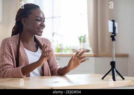 Giovane donna afro-americana blogger registrare nuovo video su smartphone a casa Foto Stock