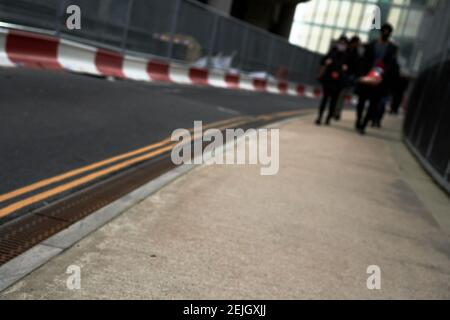 Vista sfuocata dei pedoni sulla strada con doppia linee in strada e lavori di costruzione in background durante il giorno Foto Stock
