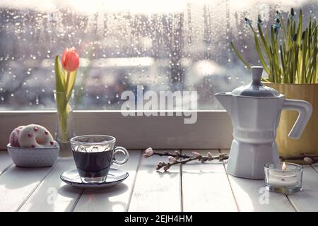 Caffè orientale in tradizionale caffettiera turca di rame con fiori sul davanzale della finestra. Davanzale in legno con tulipani arancioni e vaso di fiori di giacinto Foto Stock