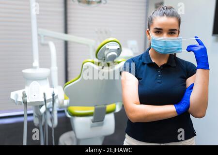 Giovane donna dentista medico in maschera si trova in ufficio Foto Stock