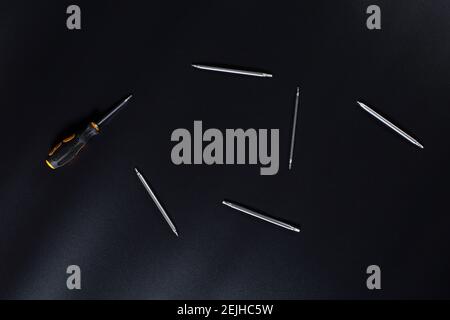 Piccoli cacciaviti per riparazioni elettroniche e altri attrezzi su sfondo nero. Foto Stock