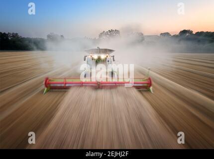 Movimento di panoramica immagine aerea con sfocatura. Trebbiatrice che lavora sul campo muovendosi direttamente alla telecamera. Vista aerea diretta utilizzando il metodo di enfatizzazione del movimento. Agricultur Foto Stock