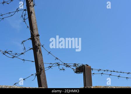 Recinzione in metallo nero con fili spelati contro i ladri nel cielo blu. Foto Stock