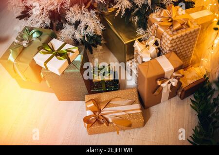 Bokeh sole illuminato in sfondo scatole da regalo sotto l'albero di Natale in interno, vista dall'alto. Foto Stock