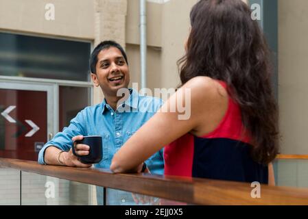 Due colleghi di lavoro che chiacchierano, ascoltano e si ritrovano nello spazio comune di un ufficio Foto Stock