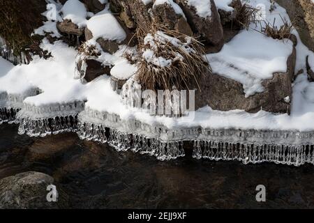 Incredibili forme di ricicoli di cristallo appesi al bordo della neve riva coperta durante l'inverno Foto Stock