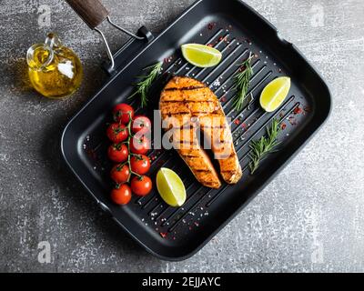 bistecca di salmone di pesce alla griglia, trota in una padella alla griglia, piccante, pomodoro, primo piano, vista dall'alto Foto Stock