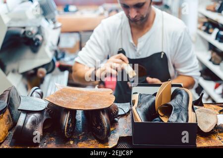 Calzolaio che mette colla sulla suola di una scarpa Foto Stock