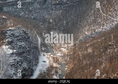 Vista dall'alto del canyon innevato e del fiume circondato da scogliere coperte di neve e alberi d'arancio Foto Stock