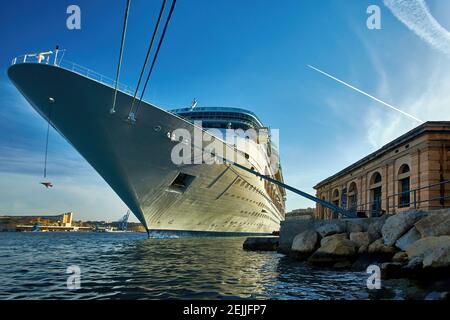 Ocean Liner nel porto dell'antica Valletta. Vista dal livello dell'acqua su enorme nave bianca contro il sole. Malta. Foto Stock