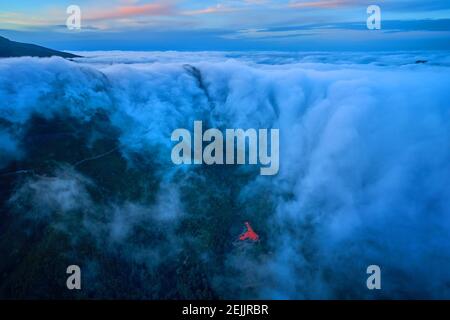 Nuvole che assomiglia a una cascata contro il cielo serale. Nuvole che scorrono nella valle. Fotografia aerea, Encumeada, viaggio isola di Madeira. Foto Stock