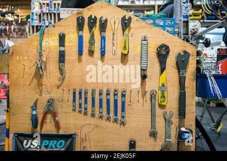 Attrezzi speciali per bici tutti allineati e appesi su una panca in un'officina di manutenzione della bicicletta Foto Stock