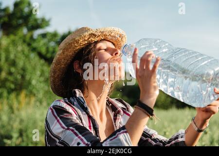 Donna contadina con boccaglio di acqua in un campo di coltura Foto Stock