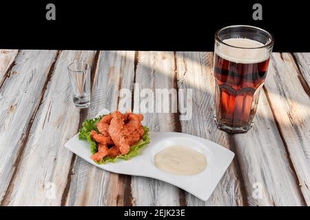 Piatto con ali di pollo con salsa rossa accompagnata da un birra scura Foto Stock