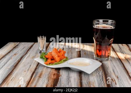 Piatto con ali di pollo con salsa rossa accompagnata da un birra scura Foto Stock